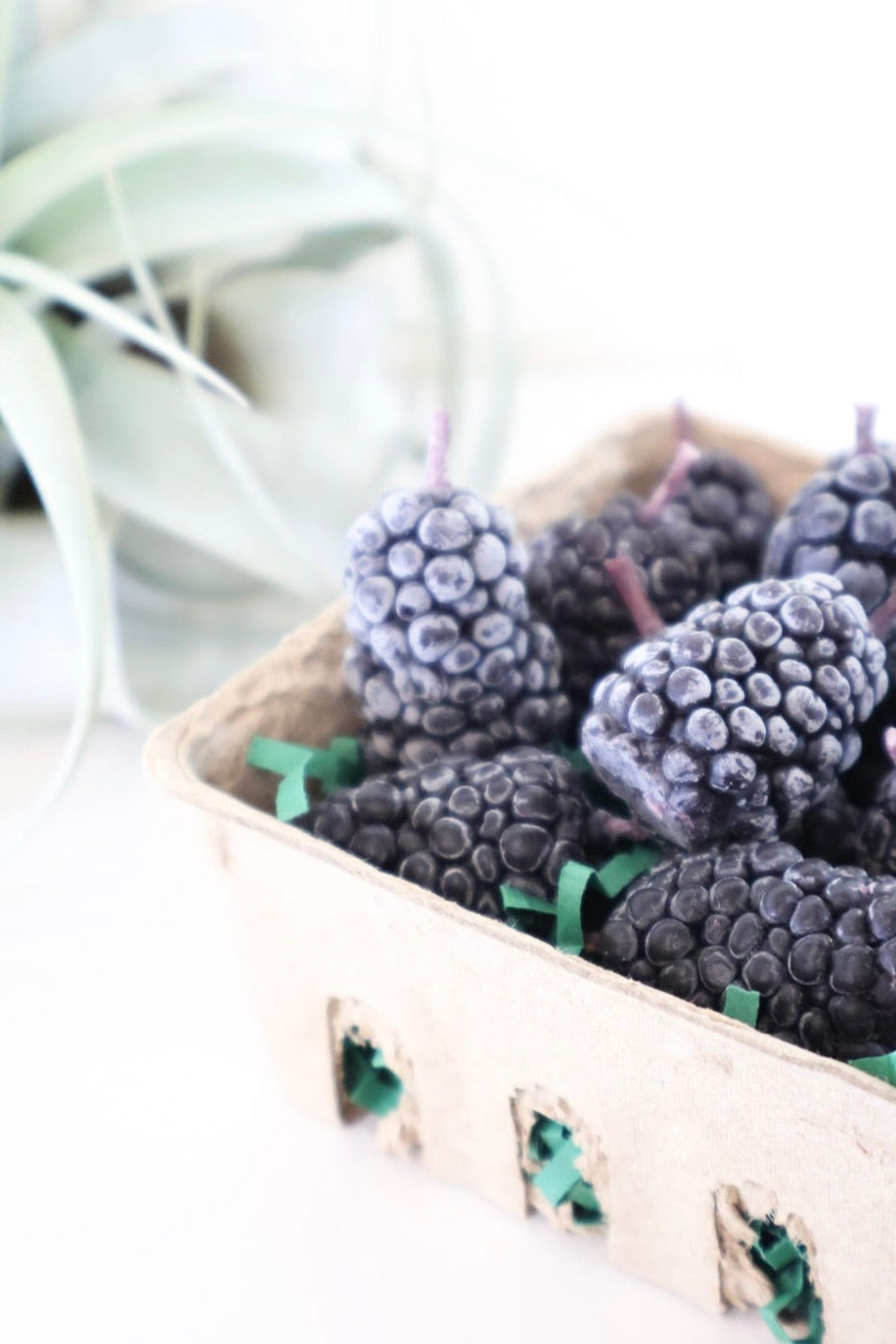 Close up of blackberry shaped beeswax candles in a tan berry box. 