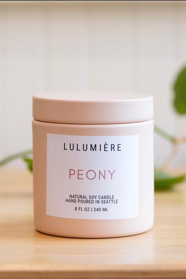 Light pastel pink metal candle with lid showing Peony scent and modern simple branding. 