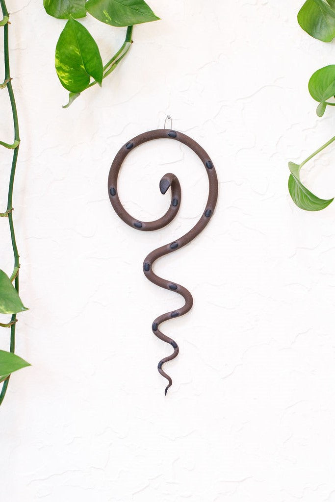 Simple contemporary ceramic snake wall decoration, with the top of the snake shaped loosely like a question mark and the tail hangs down in an organic s curve. This snake is Stevie, dark brown with light turquoise glazed head and dots.