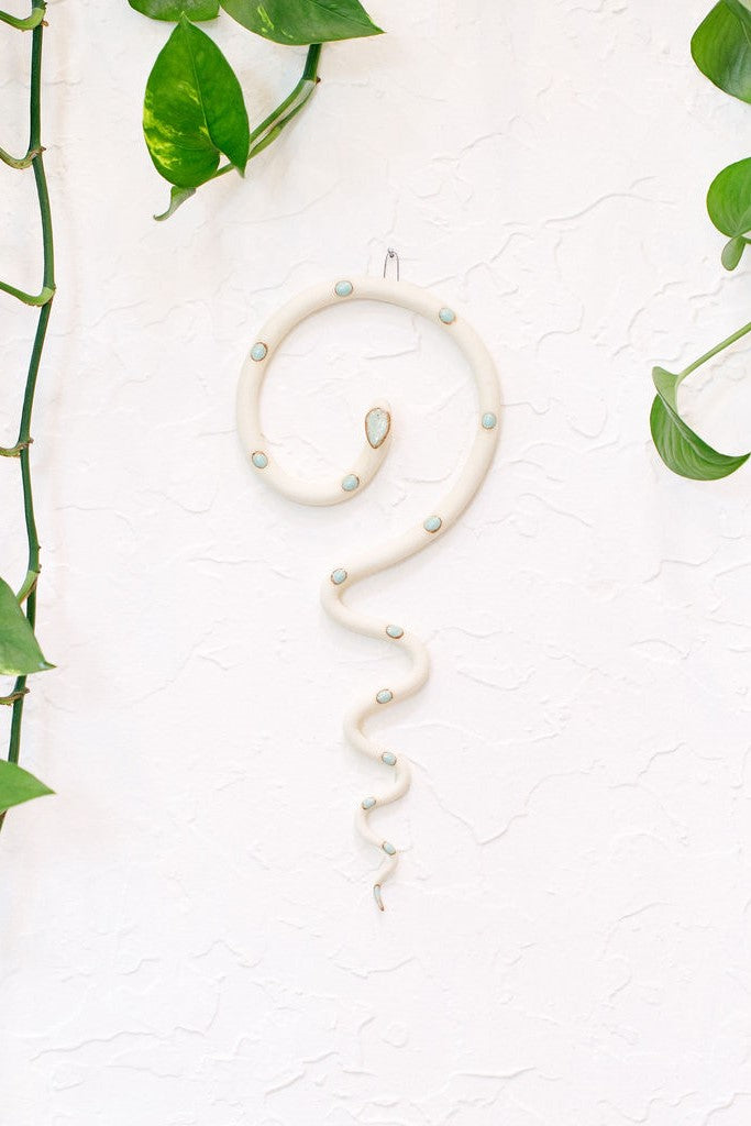 Simple contemporary ceramic snake wall decoration, with the top of the snake shaped loosely like a question mark and the tail hangs down in an organic s curve. This snake is Sylvia, ivory with light turquoise glazed head and dots.