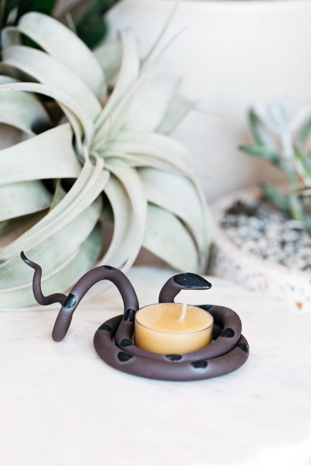 Organically coiled black clay snake with black head and dots. This colorway is Saul. Styled with a beeswax tea light that sits in the center of the coil.