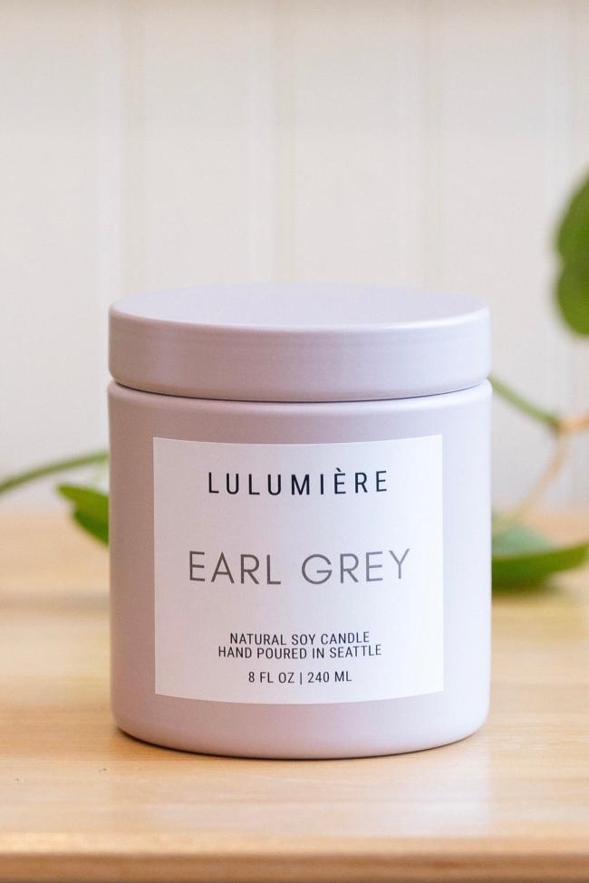 Light pastel purple metal candle with lid showing Earl Grey scent and modern simple branding. 
