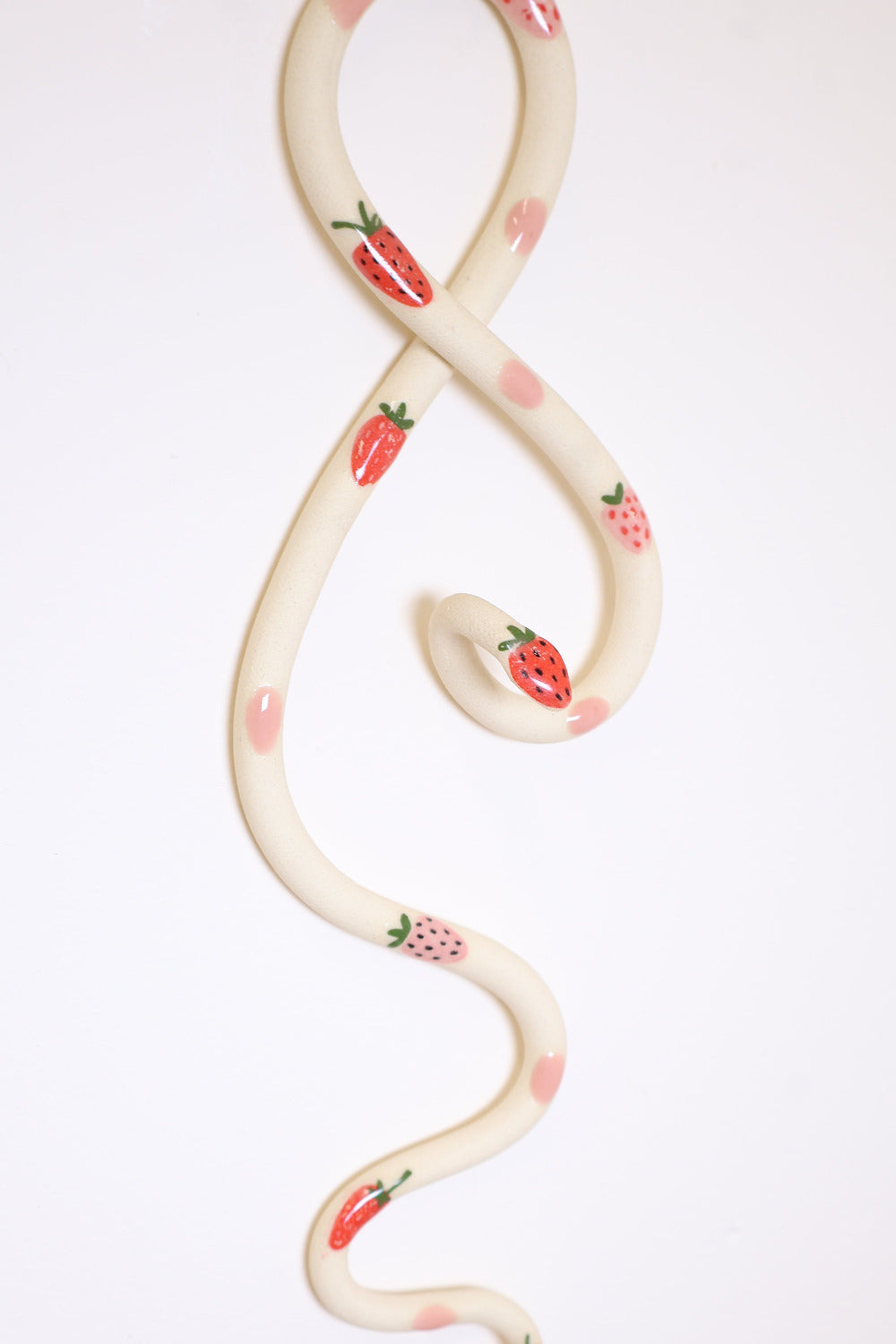 Close up of the strawberry decals and pink dots on the ceramic strawberry wall snake.