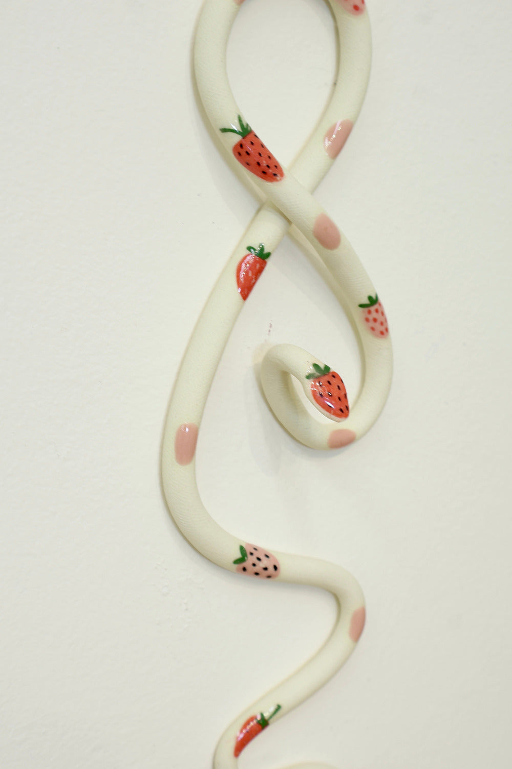 Close up of the strawberry decals and pink dots on the ceramic strawberry wall snake.