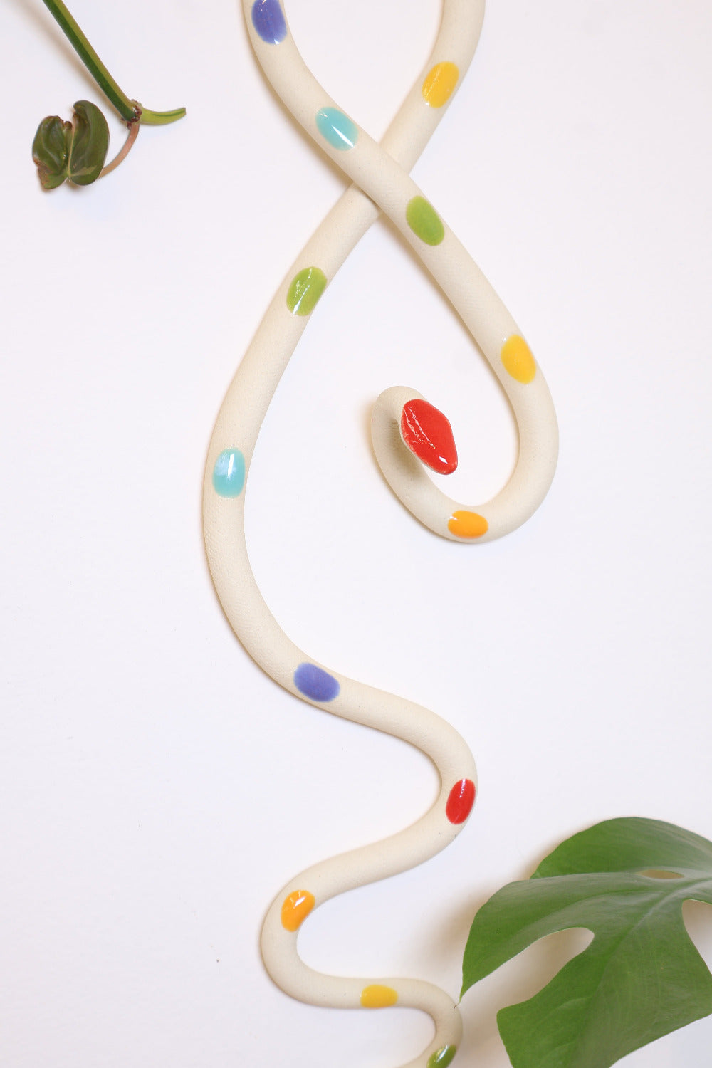Close up of the rainbow glaze dots on the ceramic wall snake. 
