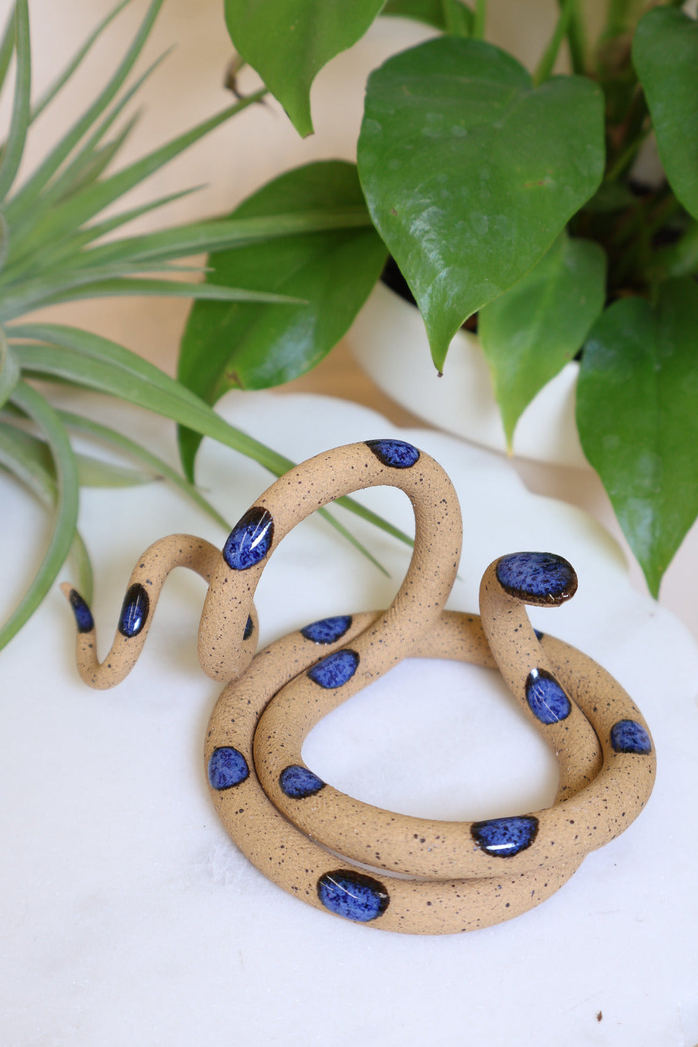 Coiled speckled tan pottery snake with blue glazed head and dots. This colorway is Selena.