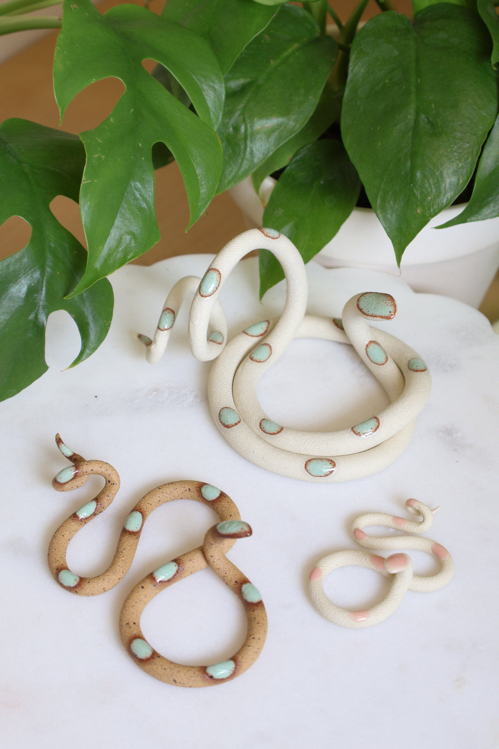 Set of three ceramic snake sculptures featuring a medium Sylvia (ivory clay with turquoise dots), a small Selma (speckled clay with turquoise dots) and a baby Sofie (ivory clay with pink dots). This is the Garden set. 