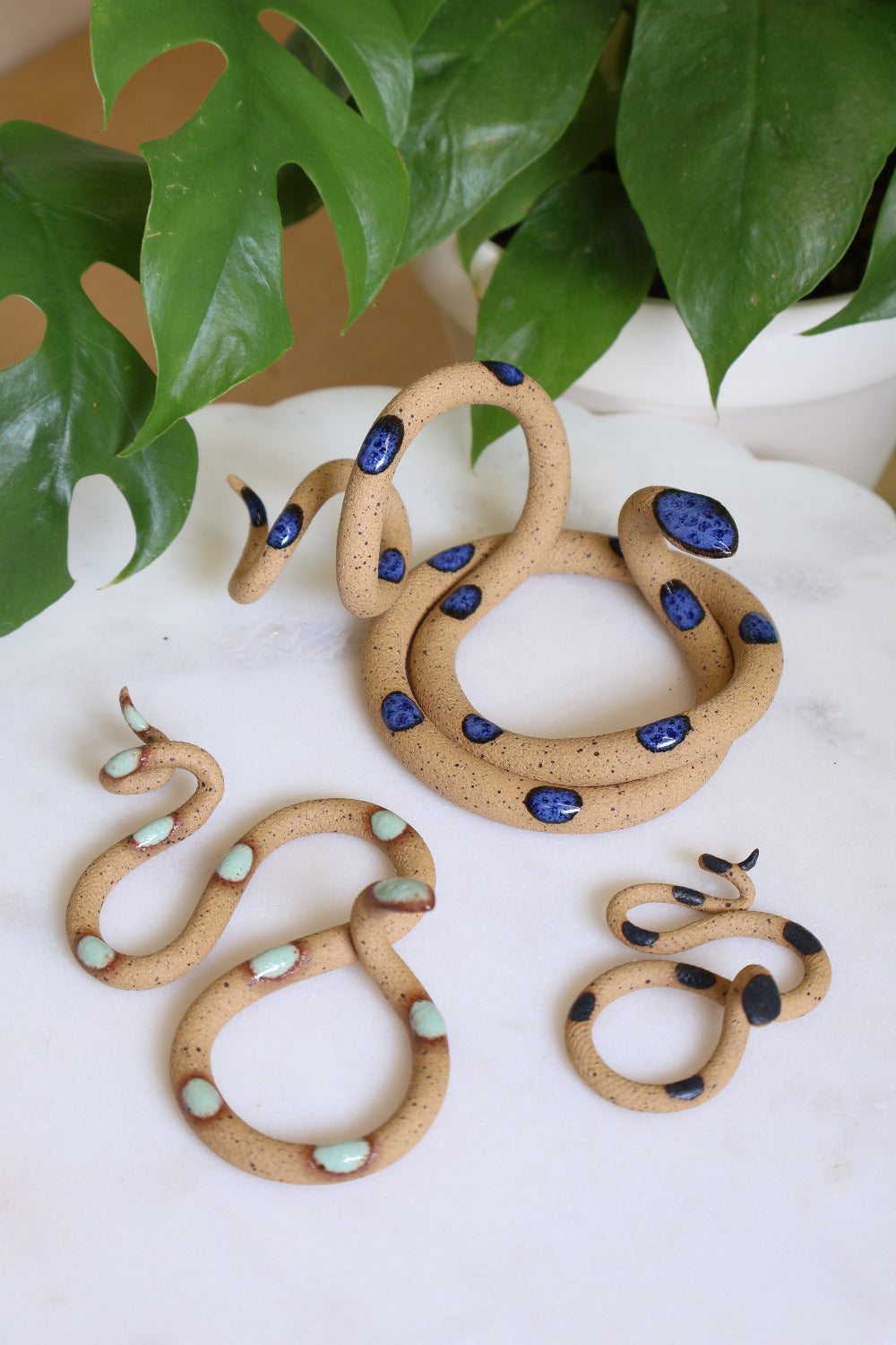 Set of three ceramic snake sculptures featuring a medium Selena (speckled clay with blue dots), a small Selma (speckled clay with turquoise dots) and a baby Sammy (speckled clay with black dots). This is the Shore set.