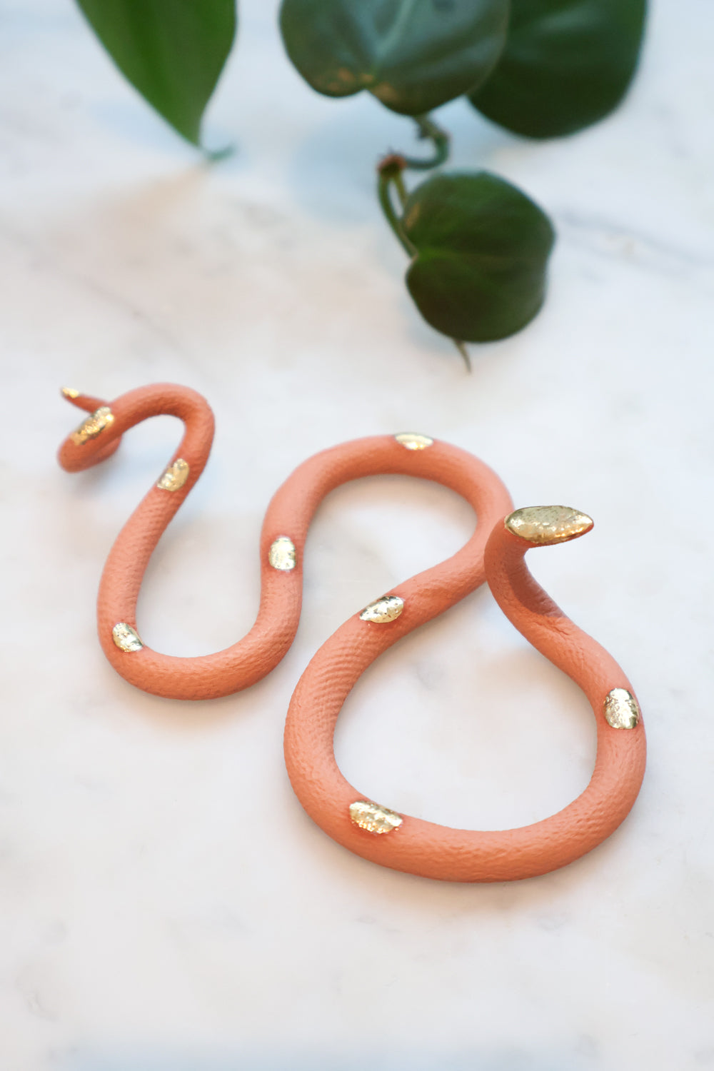 Desert sand small organic s-shaped clay snake sculpture with a terracotta clay body and gold glazed head and spots. 