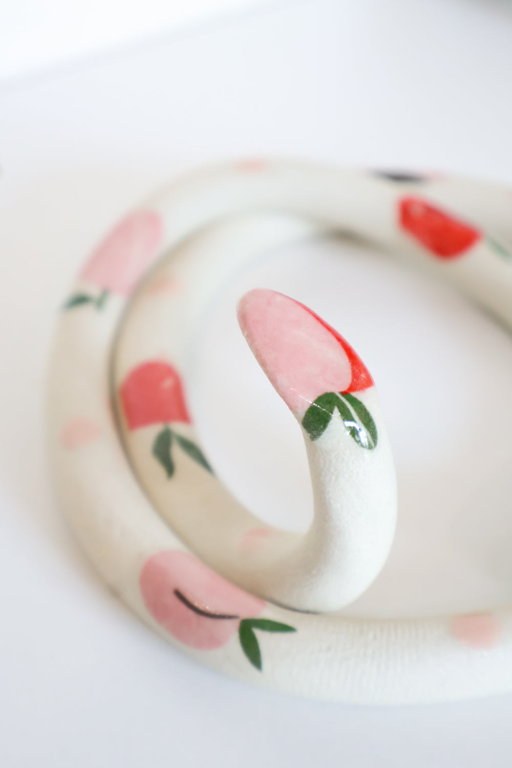 Close up of the peach decal on the head of the snake. It's pink and red with little green leaves. 