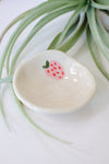 Small white ceramic dish with a strawberry design on a light background